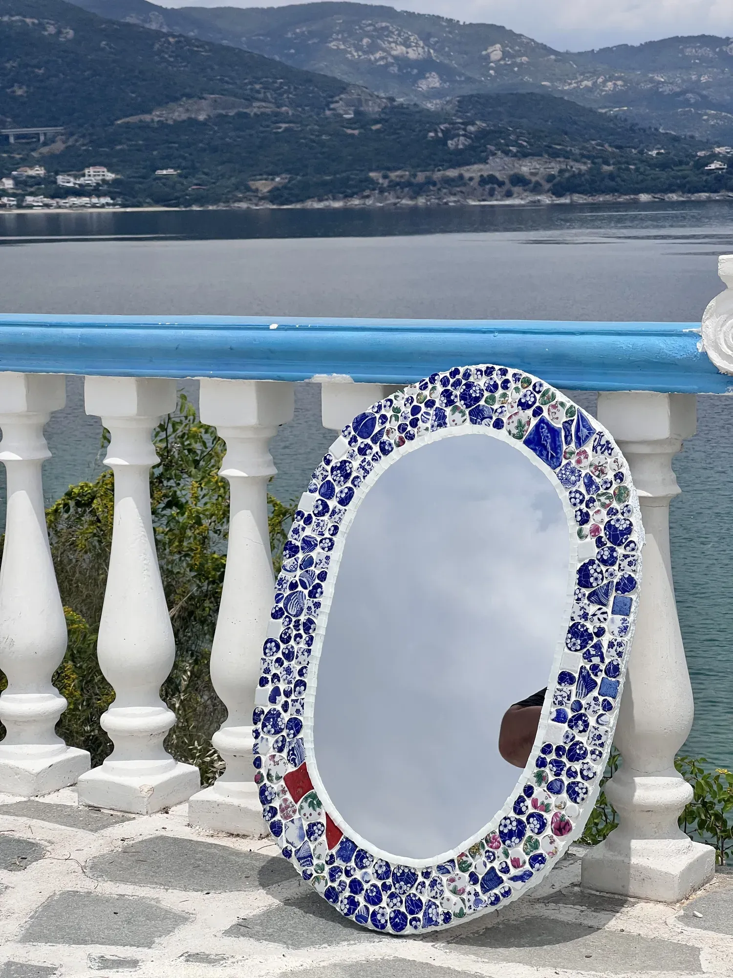 Kyma mirror leaning on a white balustrade above the sea