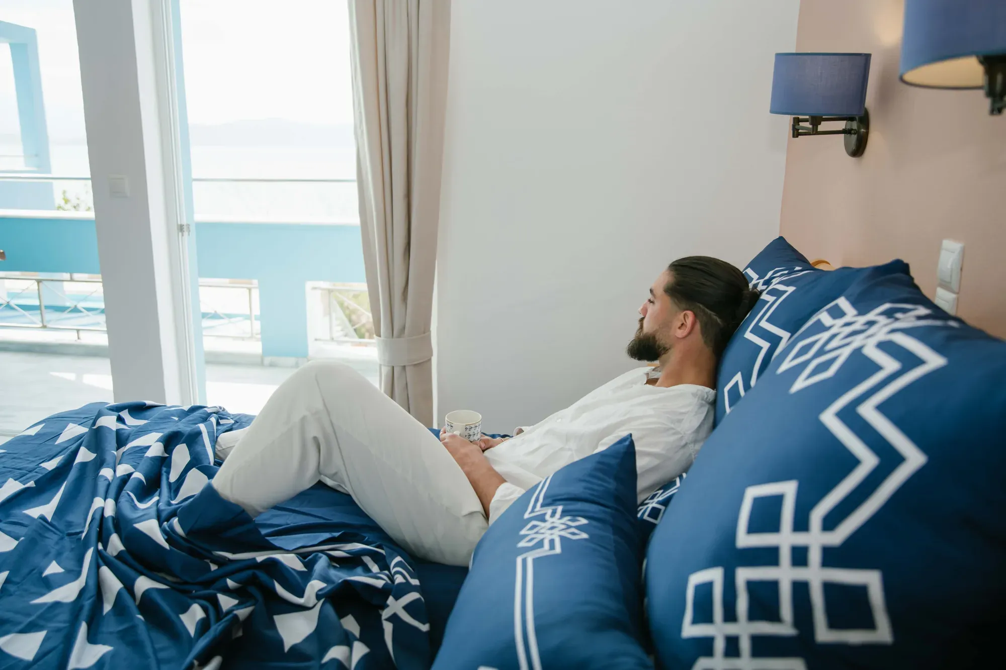 A man relaxing against Mythos Tides pillows by the window