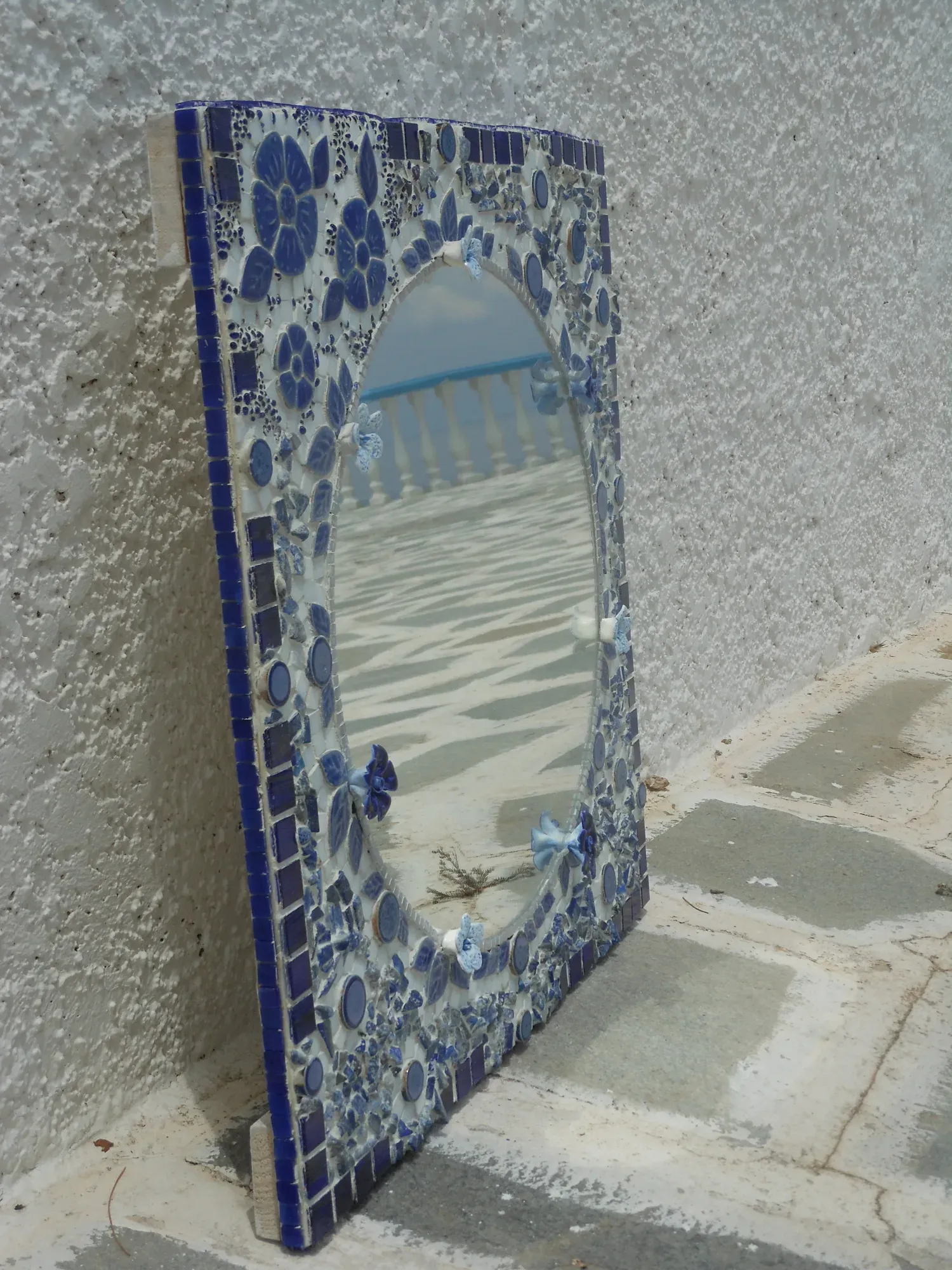 The tall floral mirror leaning on a whitewashed wall