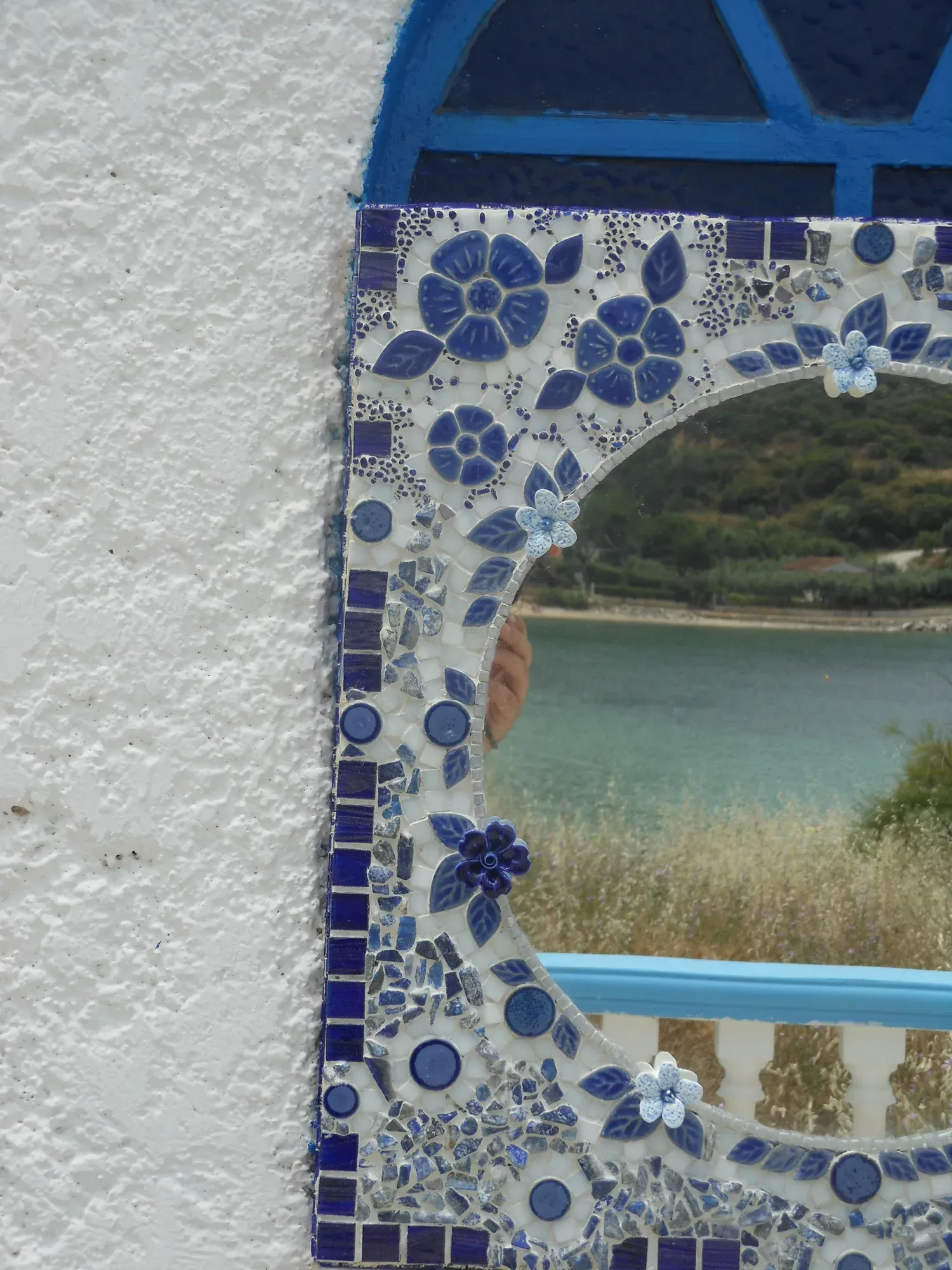 The tall floral mirror leaning on a whitewashed wall