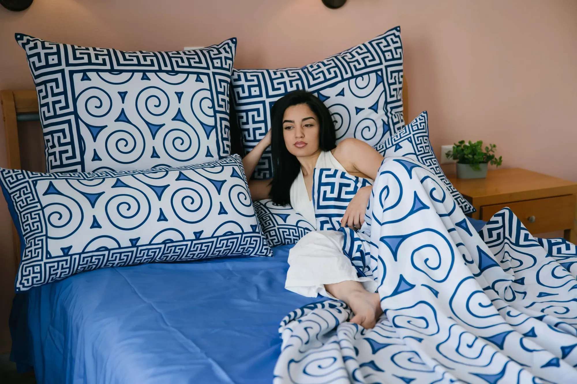 A woman resting against Aegean Whispers pillowcases