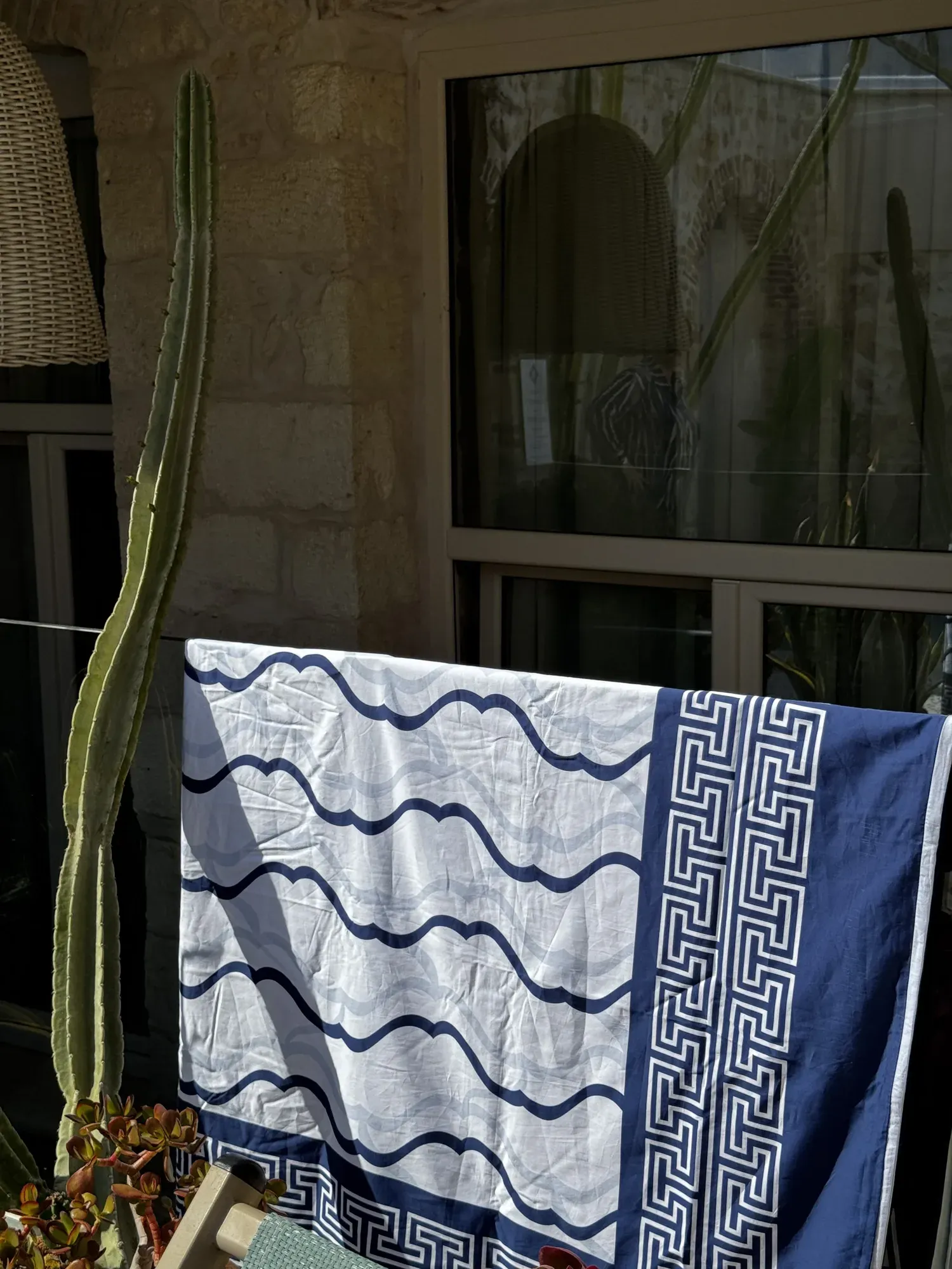 A woman lying across a Cycladic Serenity bed, the sea beyond the balcony