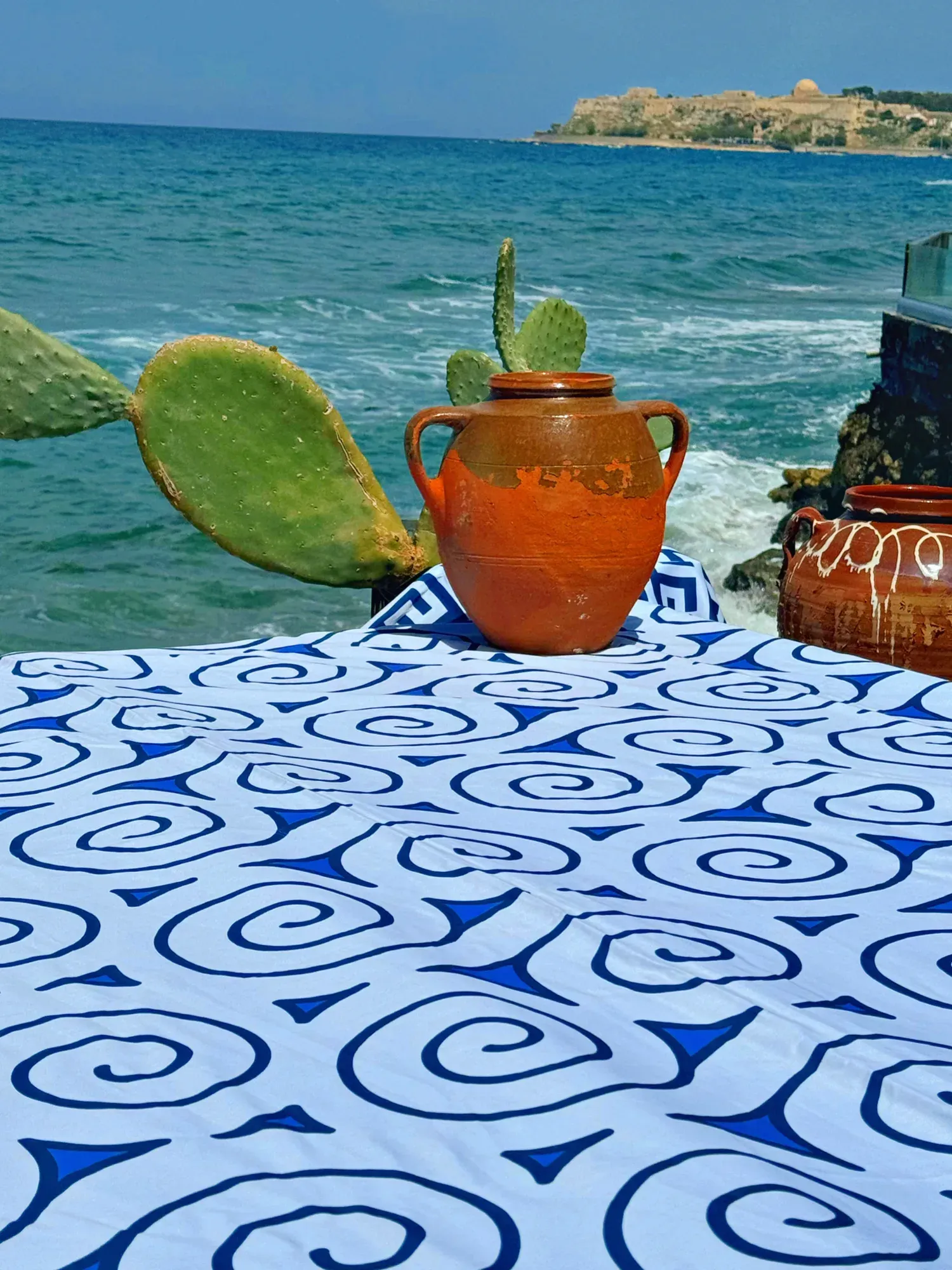 A woman leaning back among the spiral-patterned pillows of Aegean Whispers